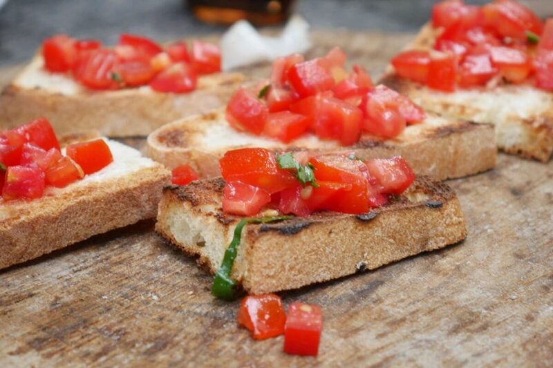 Bruschetta slices topped with diced tomato and basil on a wooden board