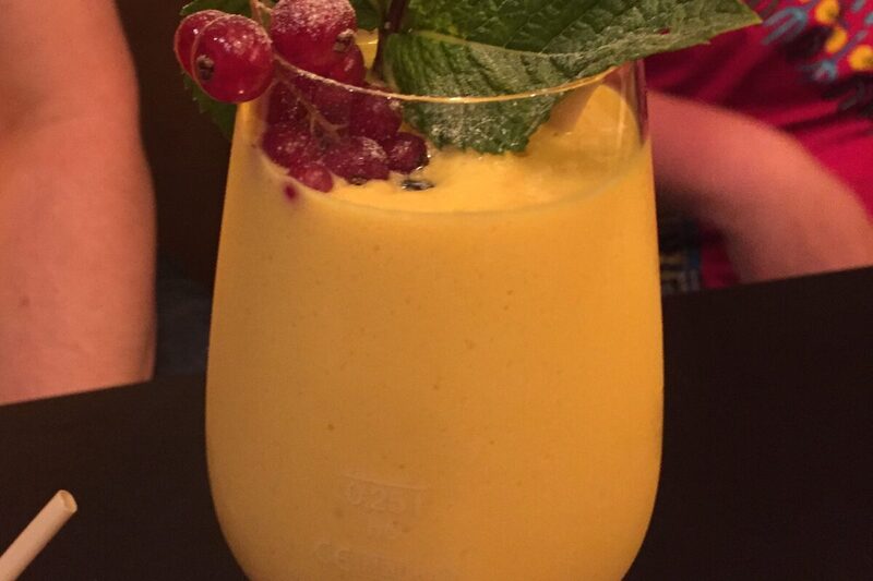 Glass of mango lassi garnished with a pinch of cardamom